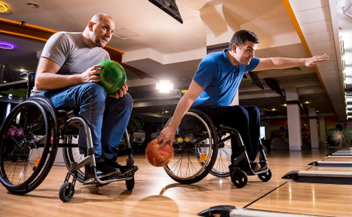 Dwie osoby na wózku grające w kręgle