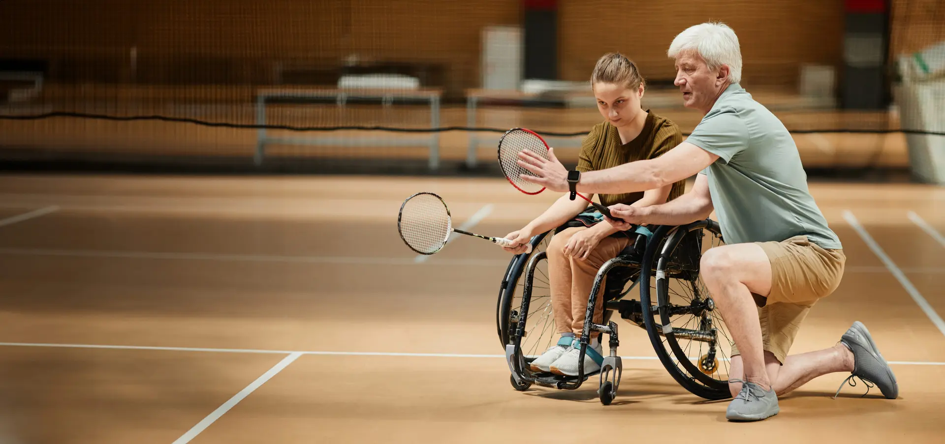 Zawodniczka na wózku ucząca się z trenerem badmintona - tło AdaptiFit